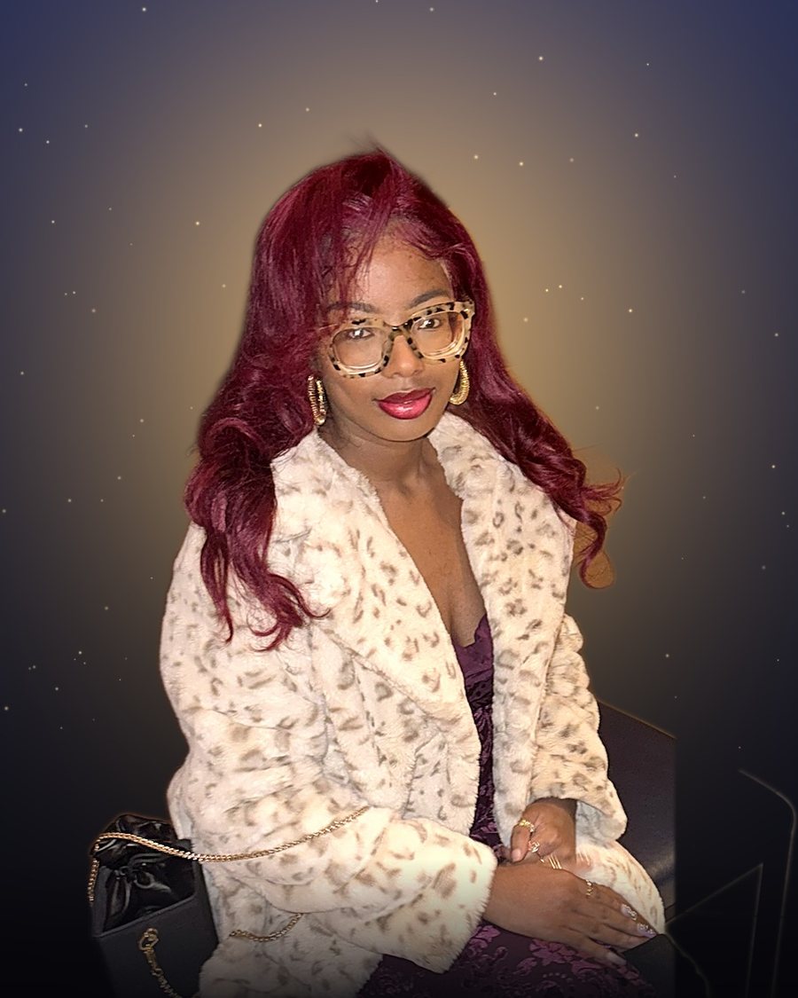 Janaee Lorraine, seated, in a cream leopard coat and plum velvet dress, glowing gold behind her
